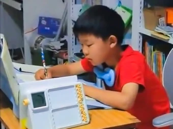 Cậu bé vừa đạp máy khâu vừa làm bài tập