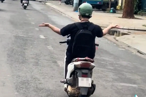 Người đàn ông buông 2 tay múa khi lái xe máy trên đường Người đàn ông buông 2 tay múa khi lái xe máy trên đường