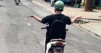 Người đàn ông buông 2 tay múa khi lái xe máy trên đường