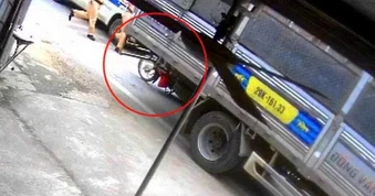 Nữ nhân viên giao hàng đứng nghe điện thoại bị xe tải cuốn vào gầm