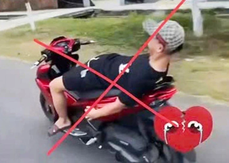 Không đội mũ bảo hiểm, buông cả 2 tay nằm dài trên yên khi lái xe máy trên đường Không đội mũ bảo hiểm, buông cả 2 tay nằm dài trên yên khi lái xe máy trên đường