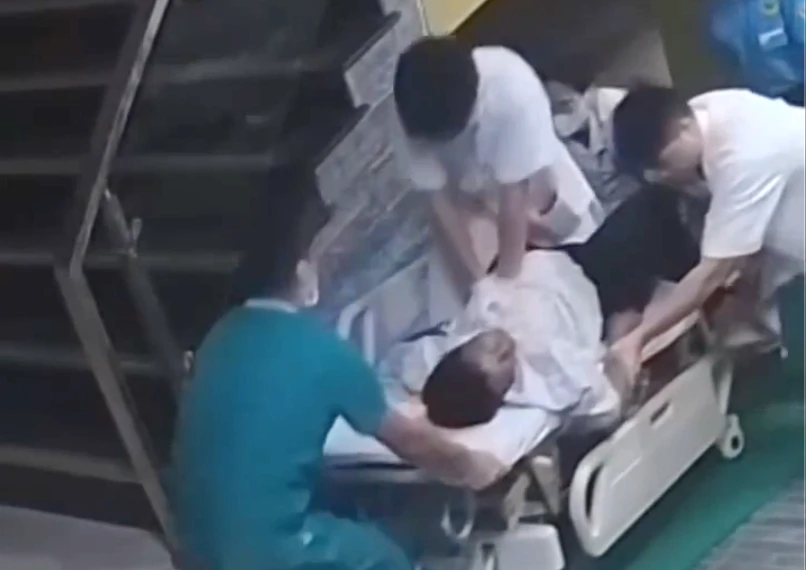 Bác sĩ trẻ ngồi trên băng ca, ép tim cứu bệnh nhân Bác sĩ trẻ ngồi trên băng ca, ép tim cứu bệnh nhân