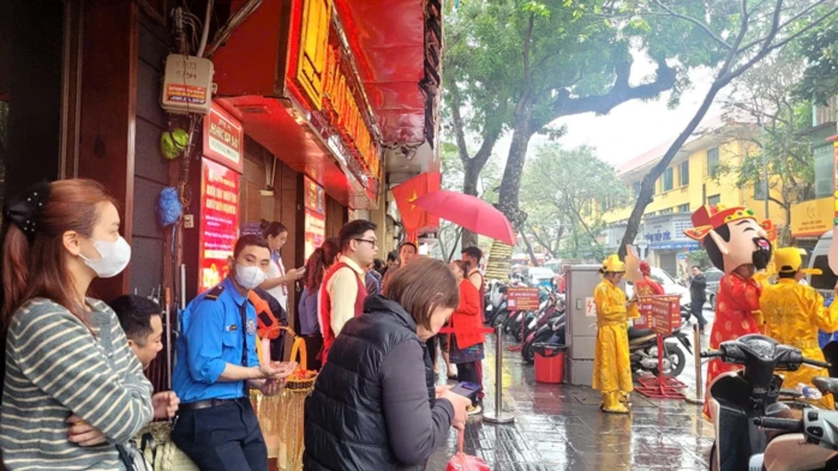 Người dân đội mưa xếp hàng chờ mua vàng trước ngày vía Thần Tài Người dân đội mưa xếp hàng chờ mua vàng trước ngày vía Thần Tài
