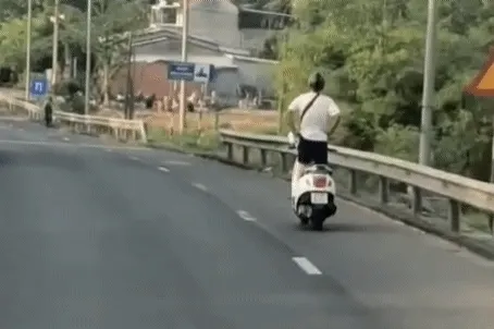 Nam tài xế buông 2 tay, đứng trên xe máy đang chạy trên quốc lộ Nam tài xế buông 2 tay, đứng trên xe máy đang chạy trên quốc lộ