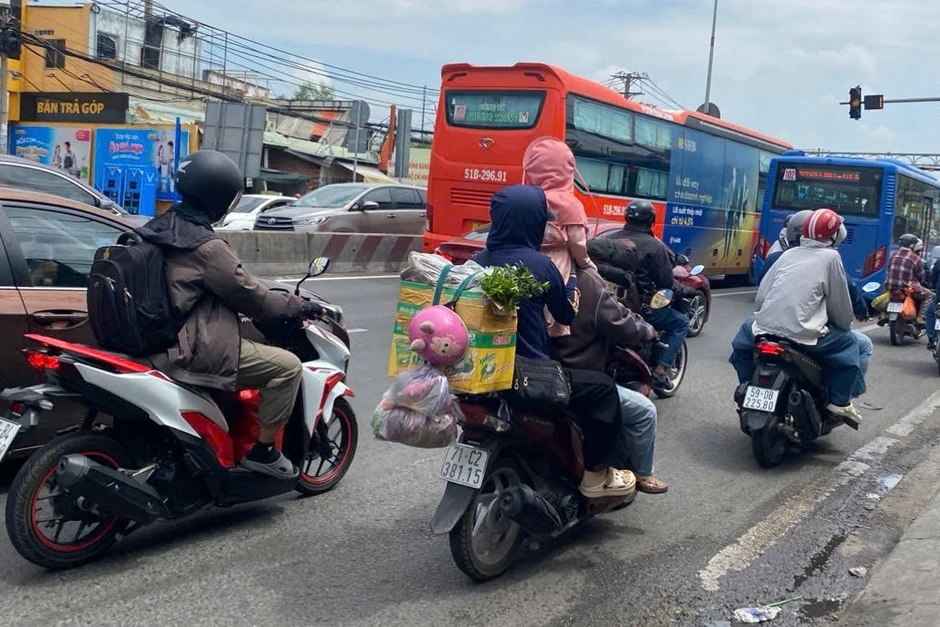 Trẻ nhỏ ngủ gục trên xe máy theo cha mẹ trở lại TPHCM sau kỳ nghỉ 30/4-1/5